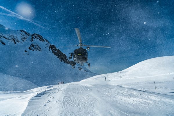 Mountain rescue team helicopter rescuing an injured skier after having a skiing accident in the Alps