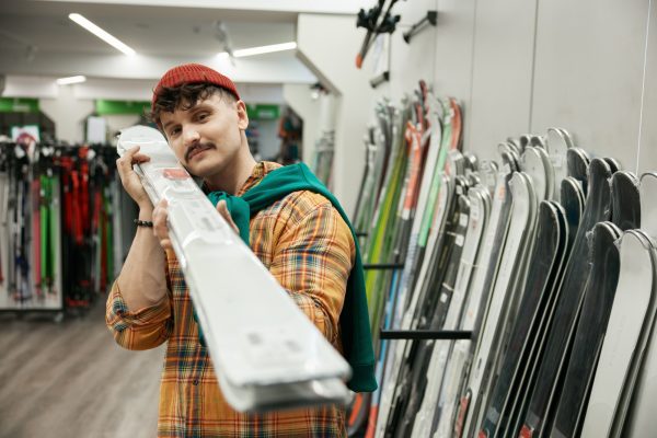 Young hipster sportsman choosing professional ski equipment at sports market